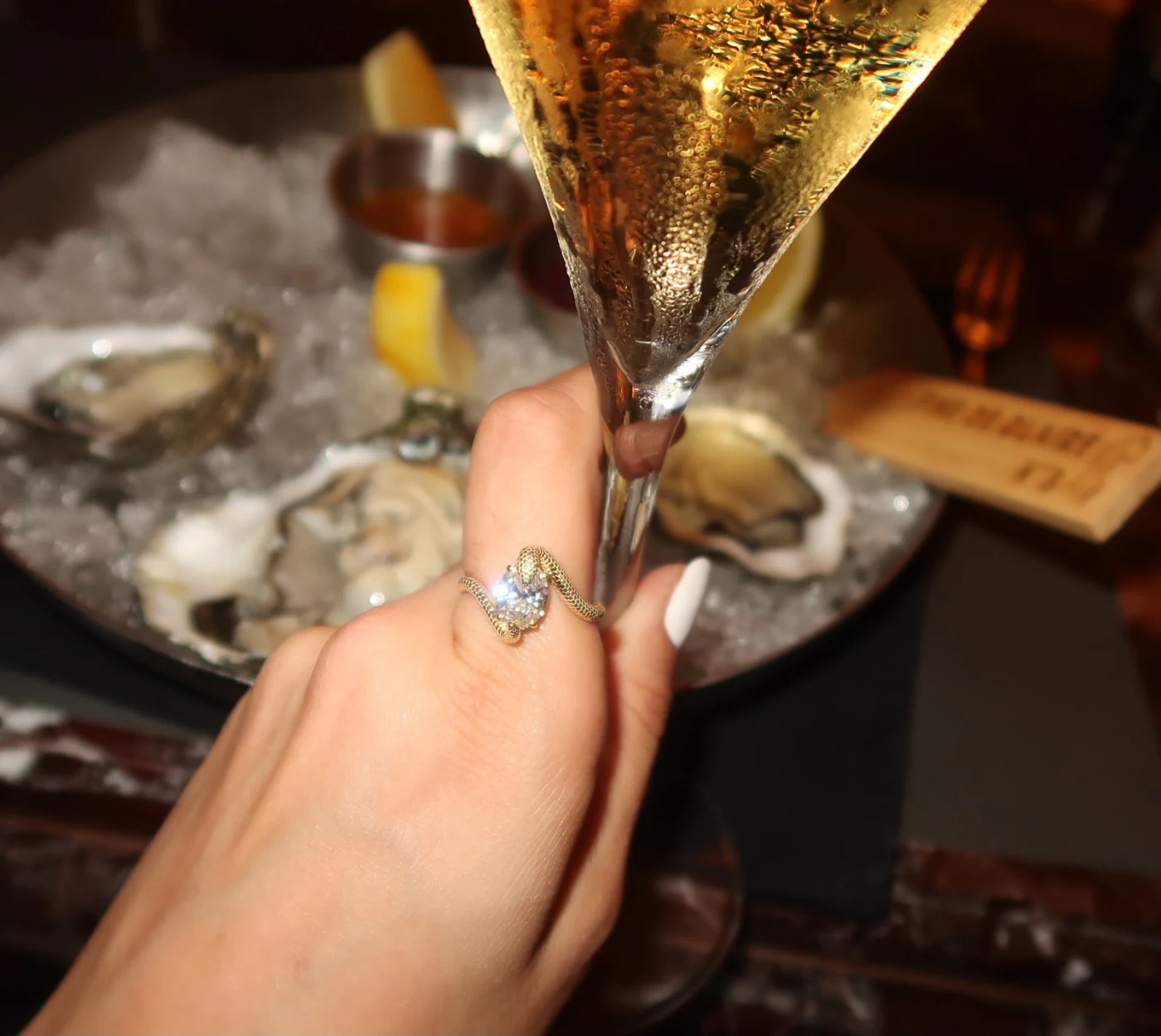 The Serpent No. 01 ring worn at a table, a glass held in the same hand