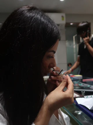 The gemmologist holding a stone in tweezers to her eye at a trading counter