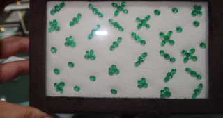 A velvet box of small round emeralds laid out and matched for colour and size